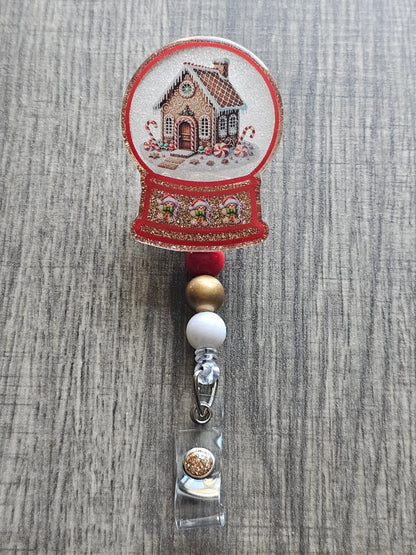 A badge reel with a snow globe design featuring a gingerbread house surrounded with snow