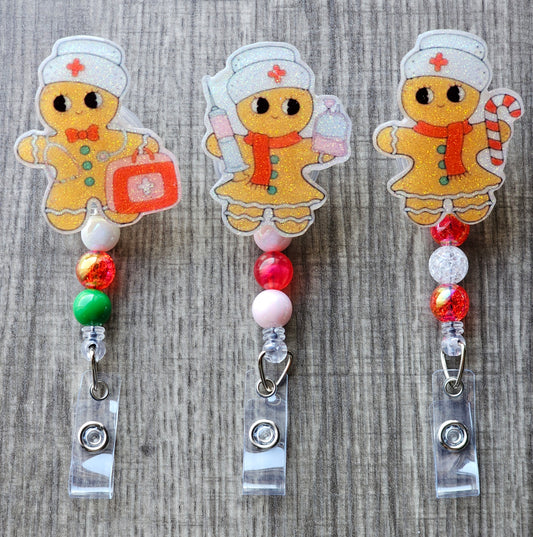 A badge reel collection features three adorable gingerbread nurses, each adorned with a classic nurse hat. One holds a syringe, another carries a first aid kit, and the third holds a festive candy cane. 