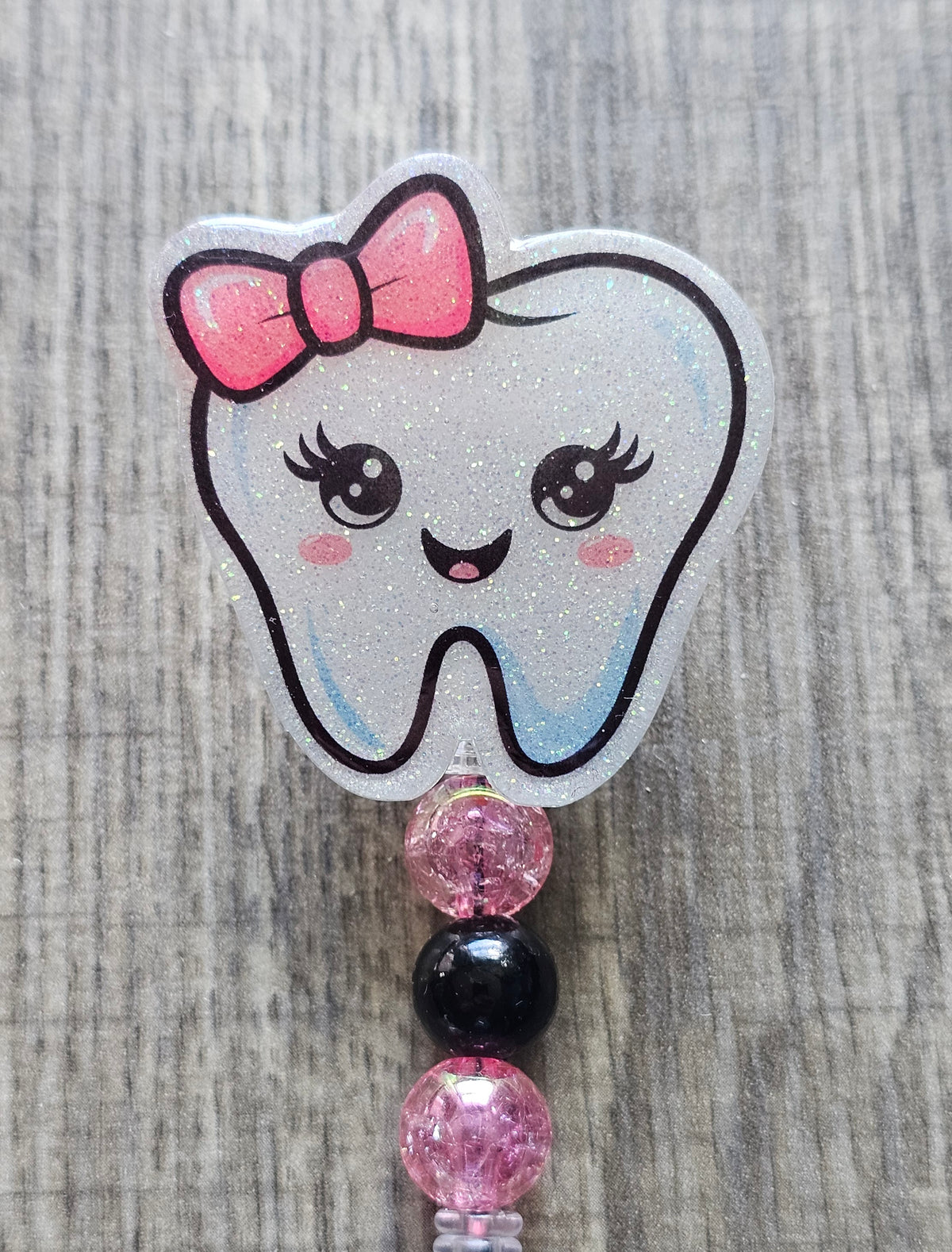Adorable tooth character with a pink bow on its head and coordinating beads badge reel.