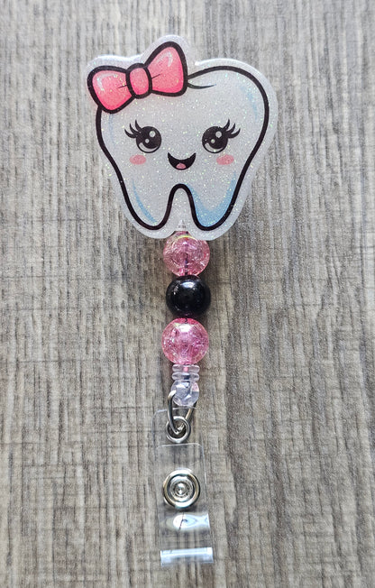 Adorable tooth character with a pink bow on its head and coordinating beads badge reel.