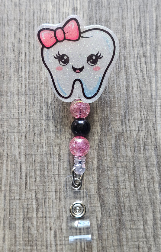 Adorable tooth character with a pink bow on its head and coordinating beads badge reel.
