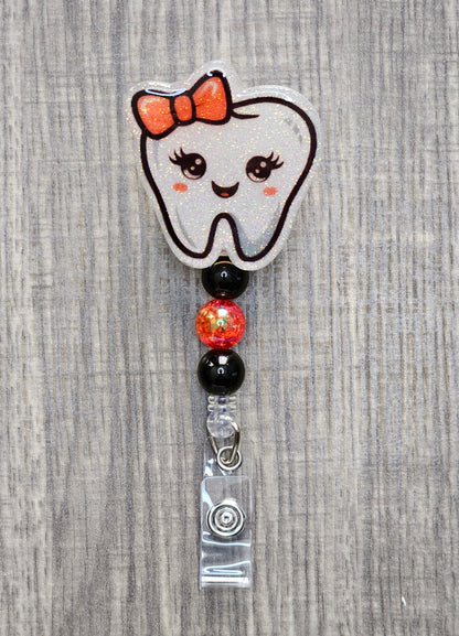 Adorable tooth character with a red bow on its head and coordinating beads badge reel.