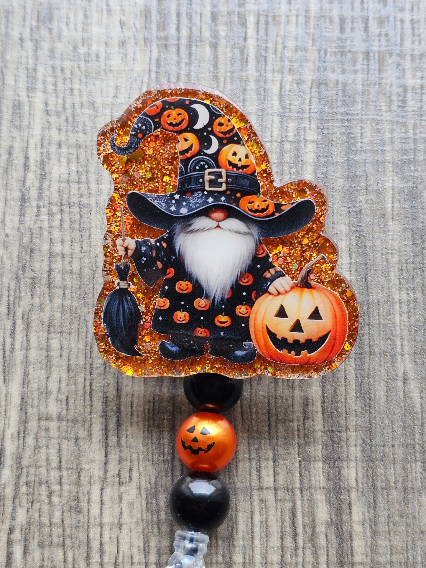 Gnome holding a brrom in a wizard costume featuring pumpkins holding a Jack-O-Lantern for Halloween