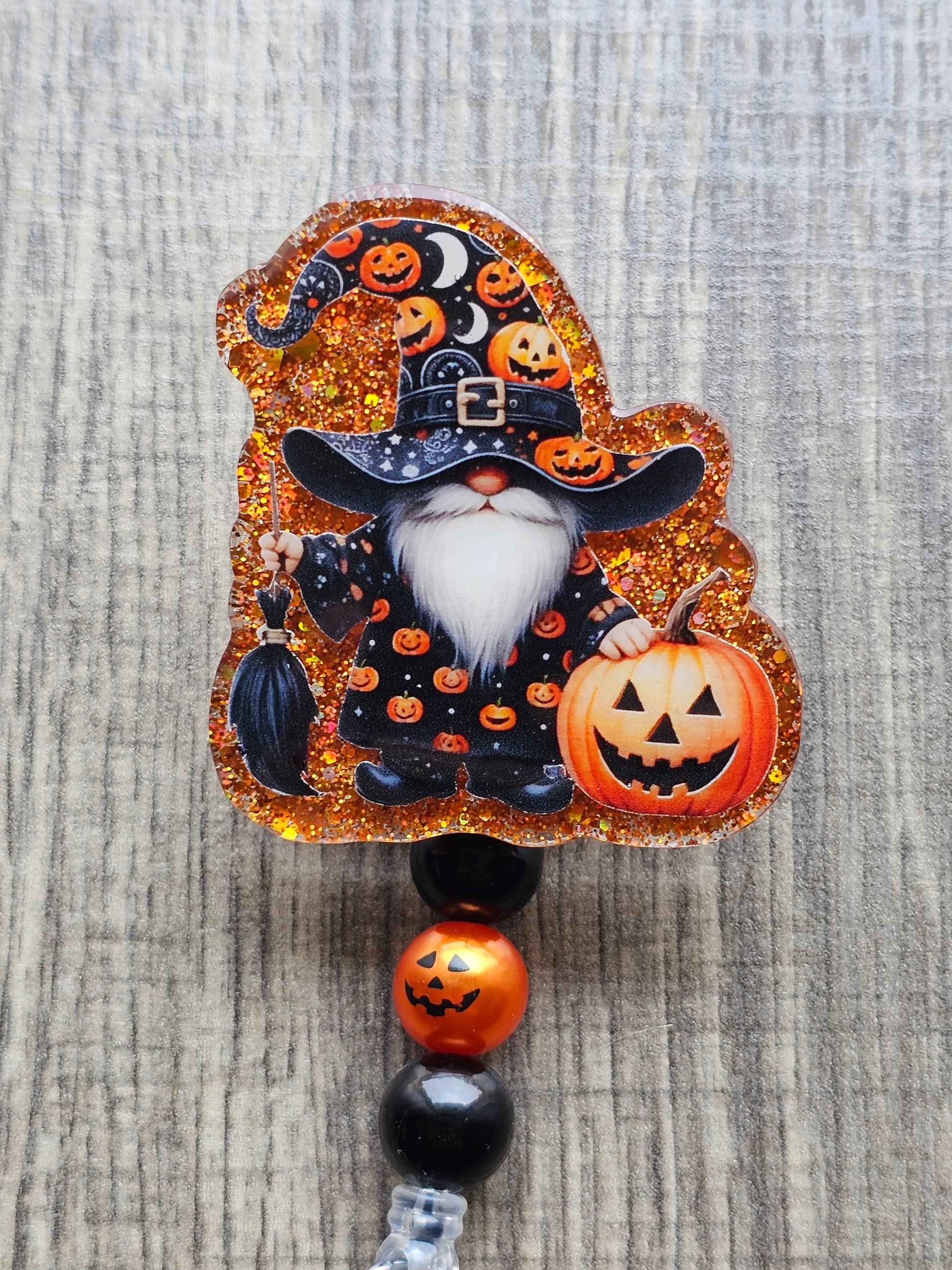 Gnome holding a brrom in a wizard costume featuring pumpkins holding a Jack-O-Lantern for Halloween