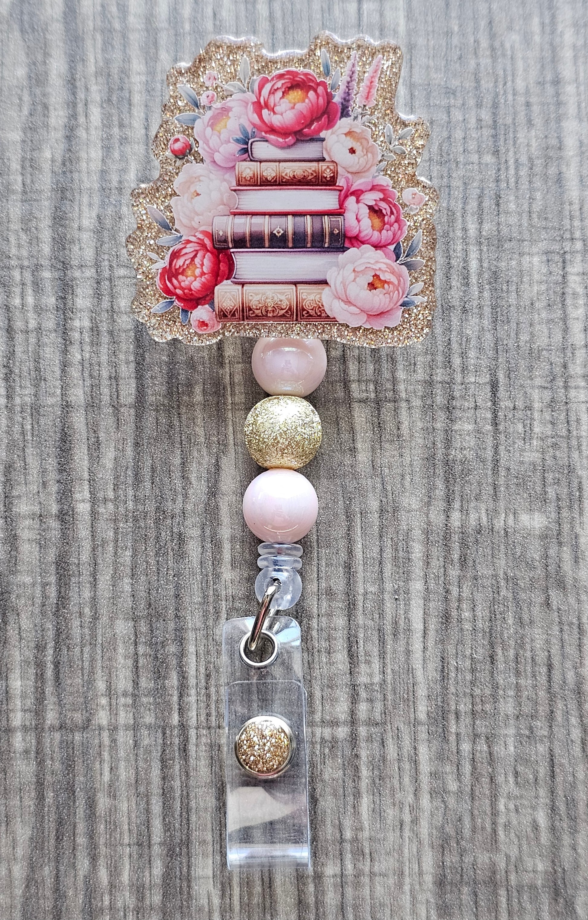  Book stack badge reel with flowers on gold acrylic with coordinating beads.