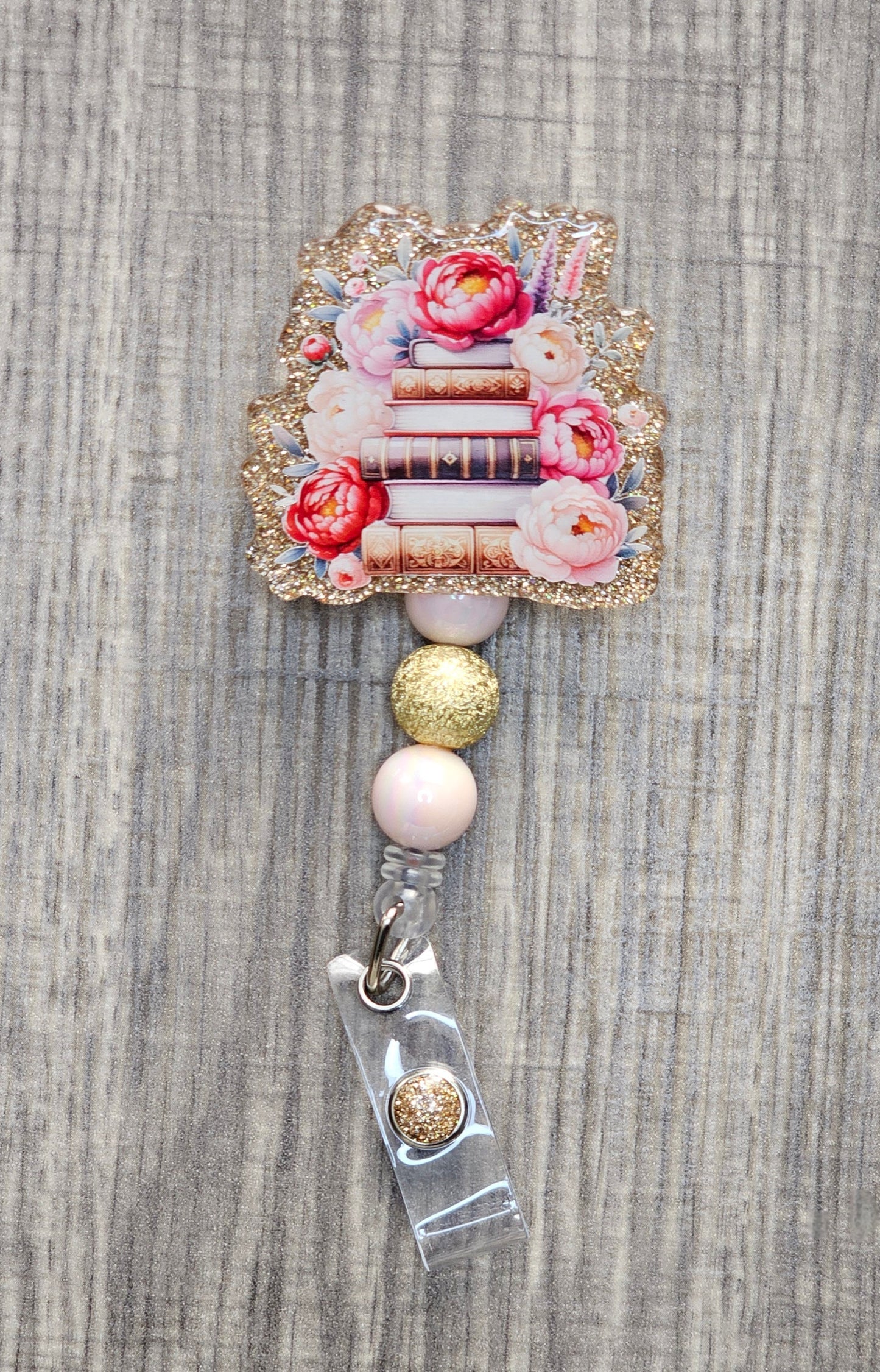 Book stack badge reel with flowers on gold acrylic with coordinating beads.