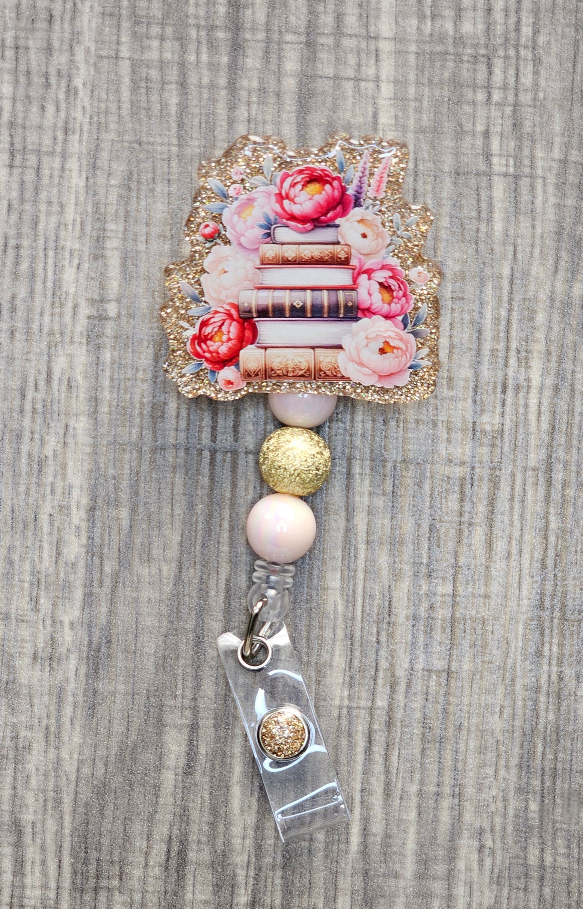 Book stack badge reel with flowers on gold acrylic with coordinating beads.