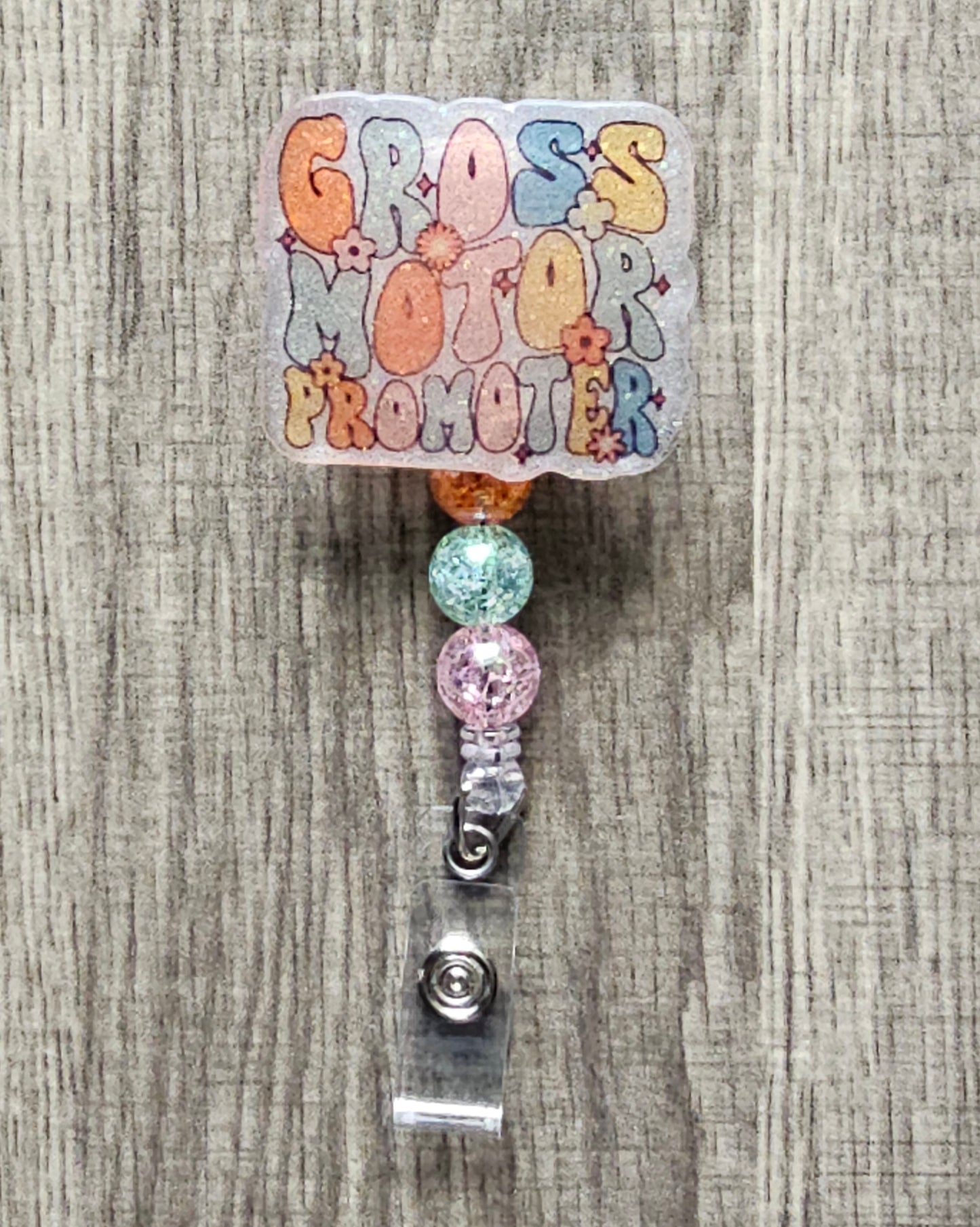 "Gross Motor Promoter" badge reel, retro font, flowers, and sparkles.