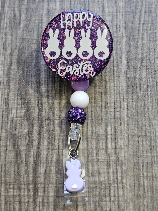  A Badge Reel purple in color with bunnies on the design with the words Happy Easter