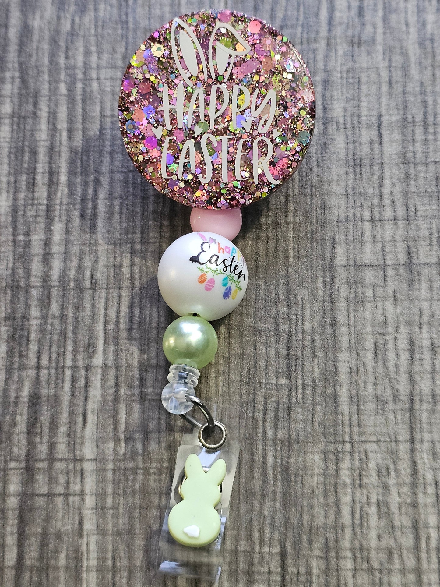  A Badge Reel pink in color with the words Happy Easter 