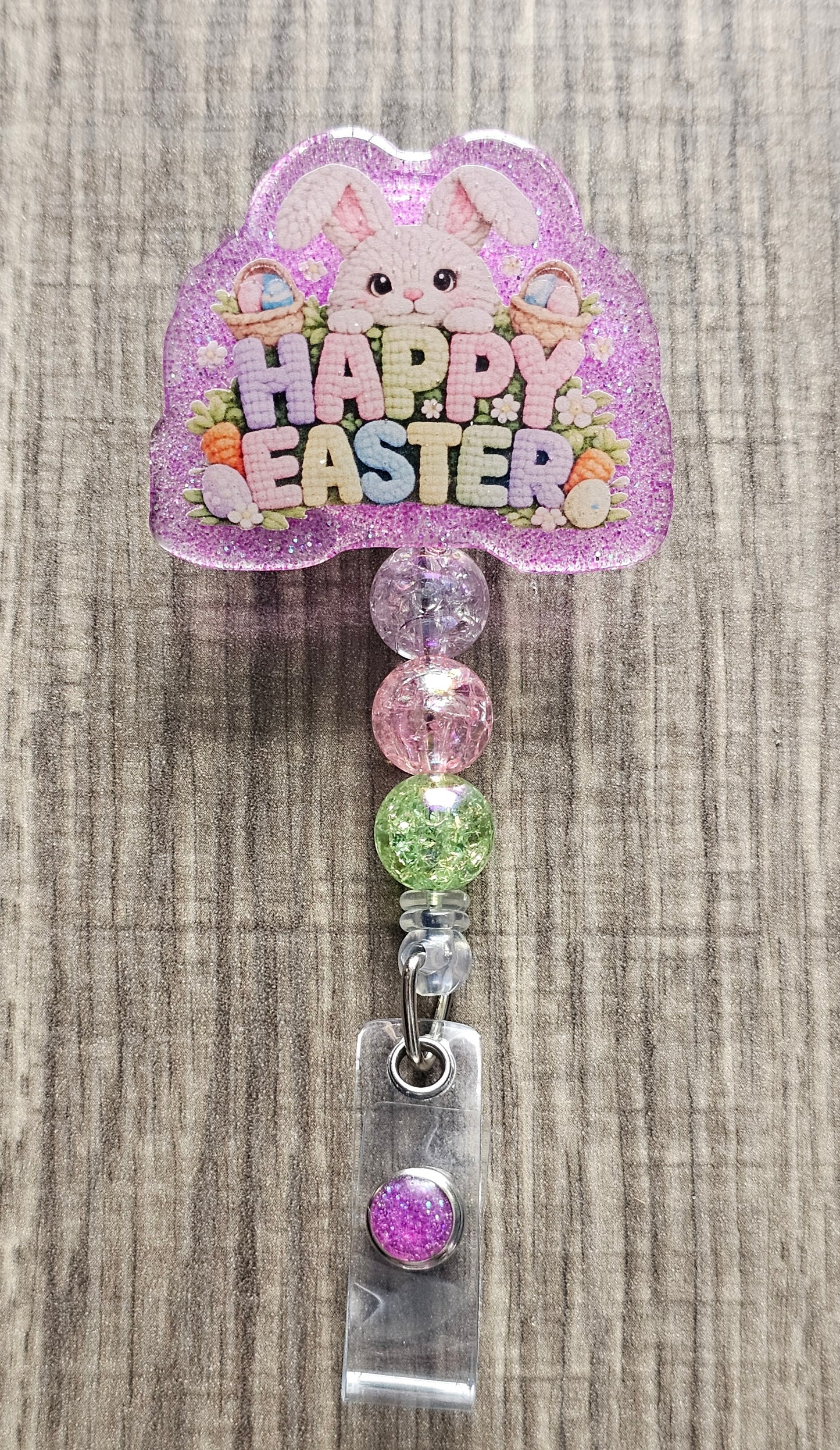 Badge reel design with a bunny peeking over bushes that say "Happy Easter" in bright colors, with baskets and eggs.