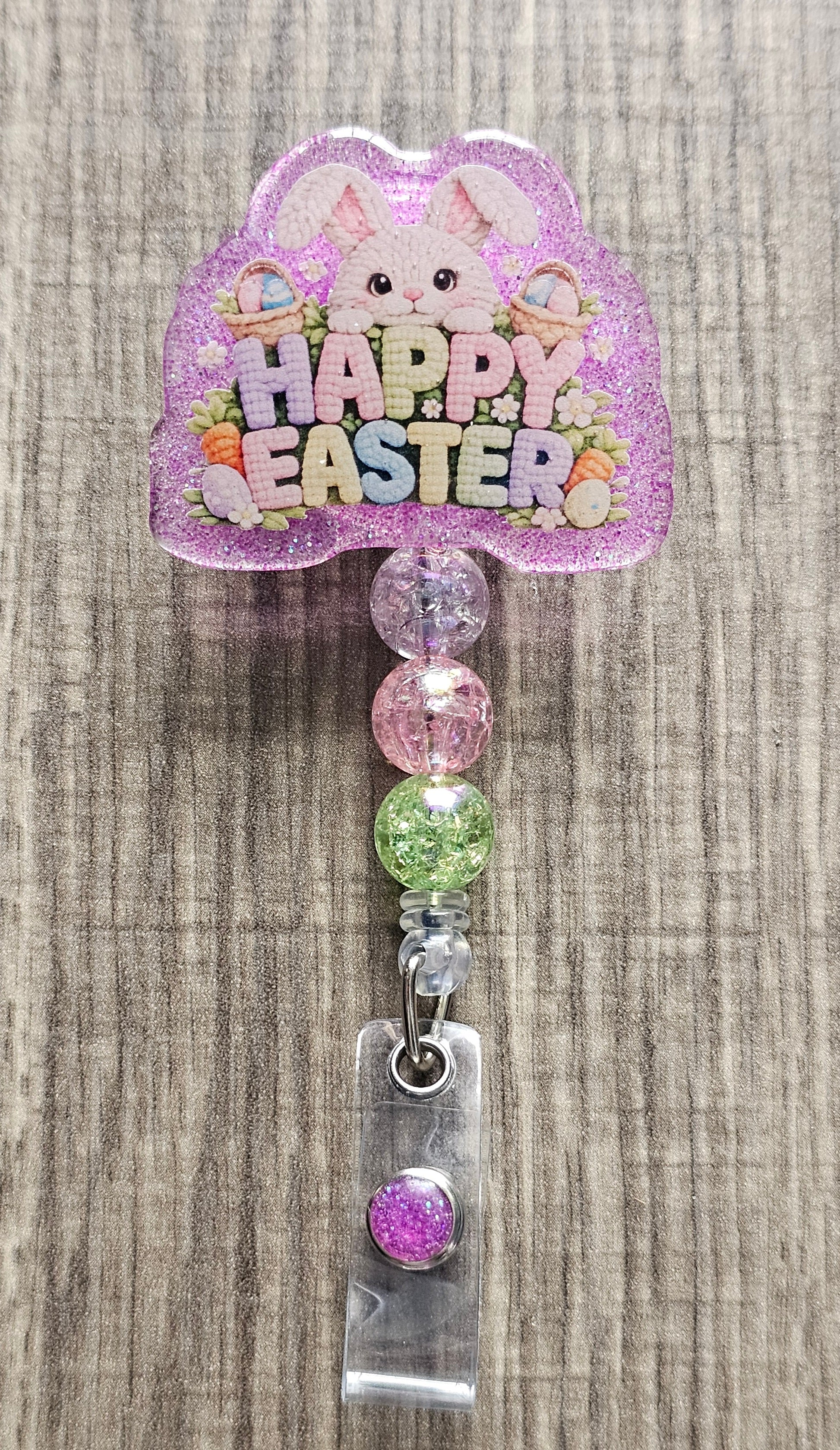 Badge reel design with a bunny peeking over bushes that say "Happy Easter" in bright colors, with baskets and eggs.