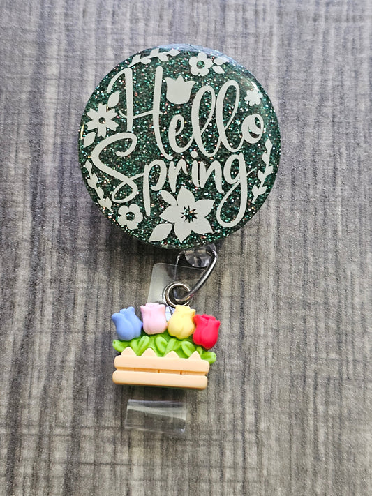  A Badge Reel with the Hello Spring with a green background and Floral design