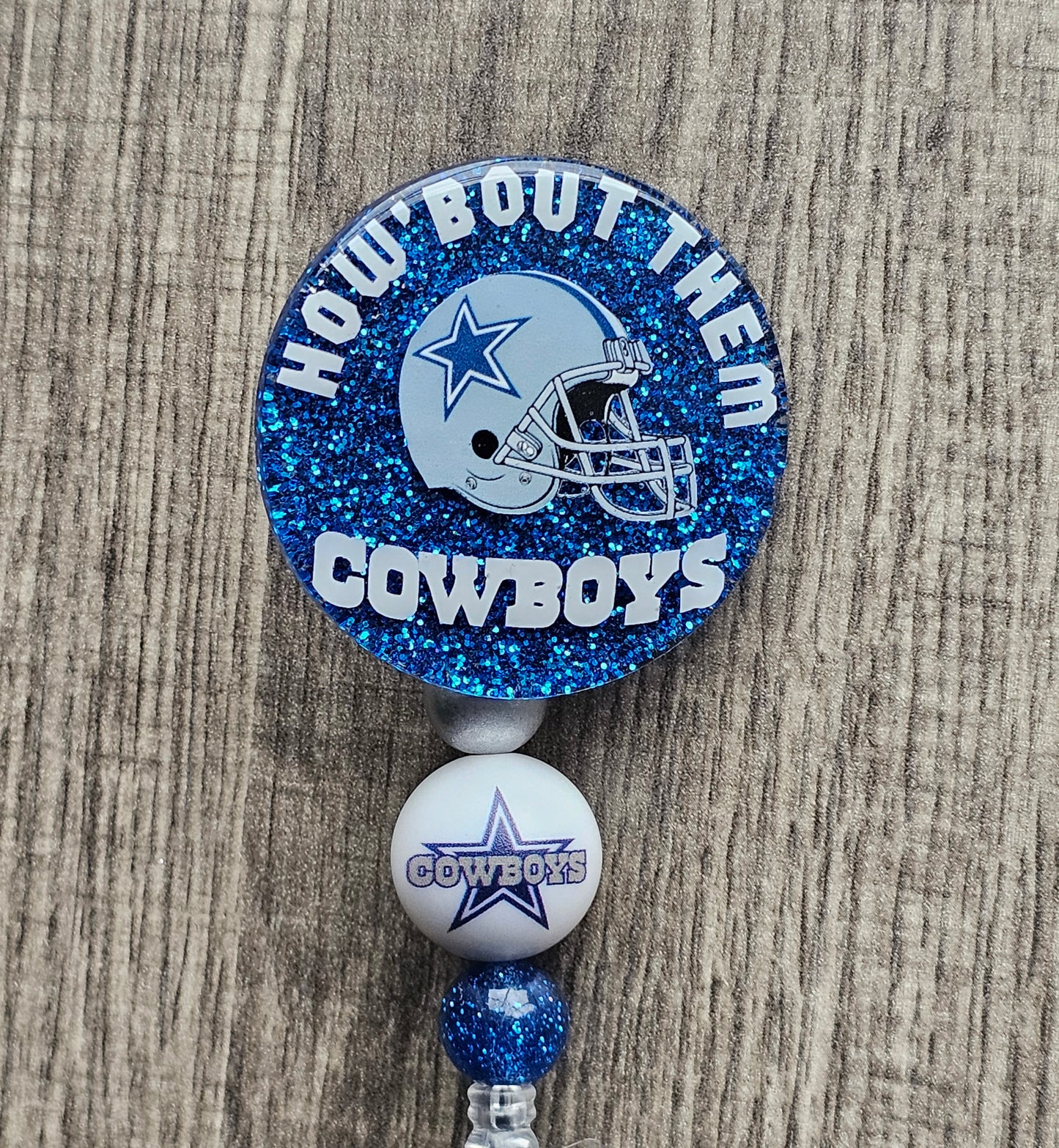 a badge reel displaying a cowboys helmet along with the words How about them Cowboys  around it