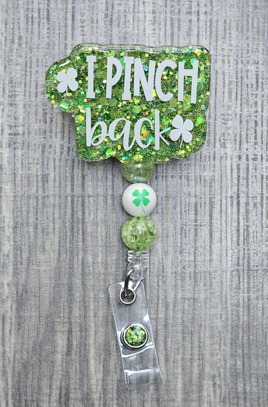 Retractable St. Patrick's Day badge reel with "I Pinch Back" text, featuring green beads and a central four-leaf clover bead.