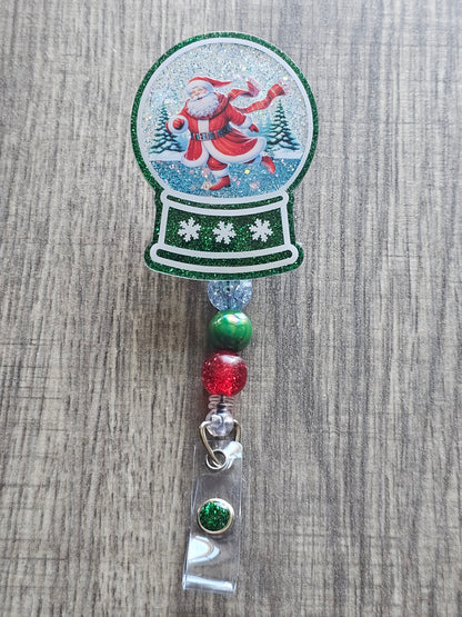 A badge reel with a snow globe design featuring Santa skating on Ice. 