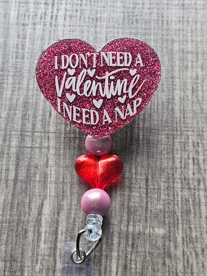 A heart shaped badge reel stating I don't need a valentine I need a nap.