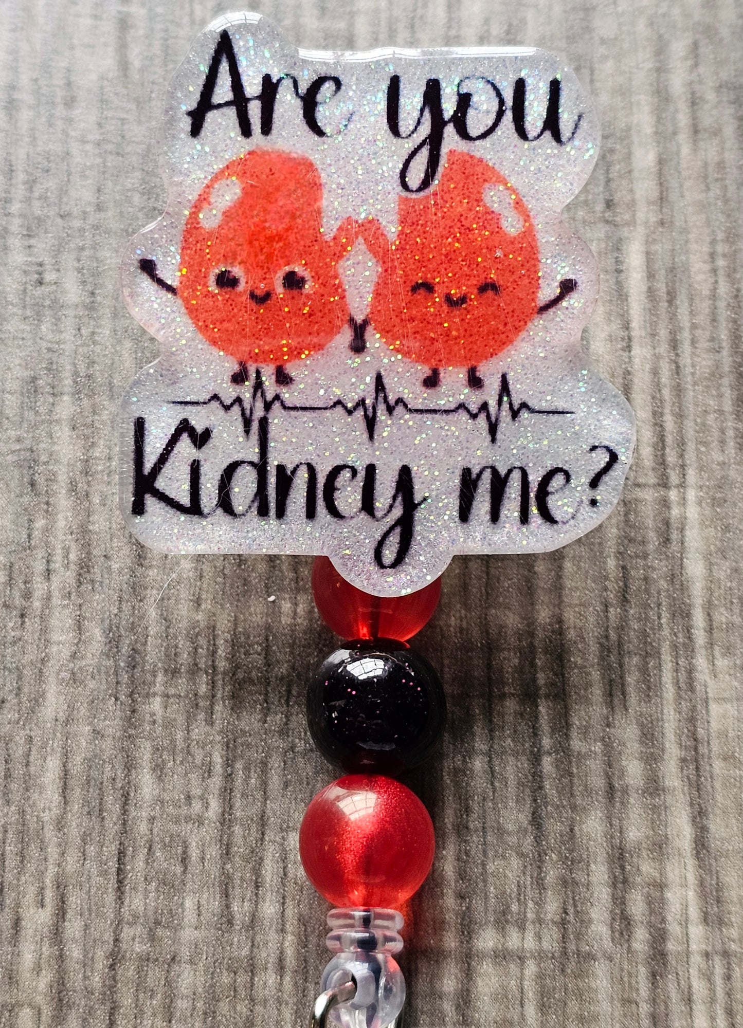 A badge reel featuring two smiling, animated kidneys holding hands with the phrase “Are You Kidney Me?