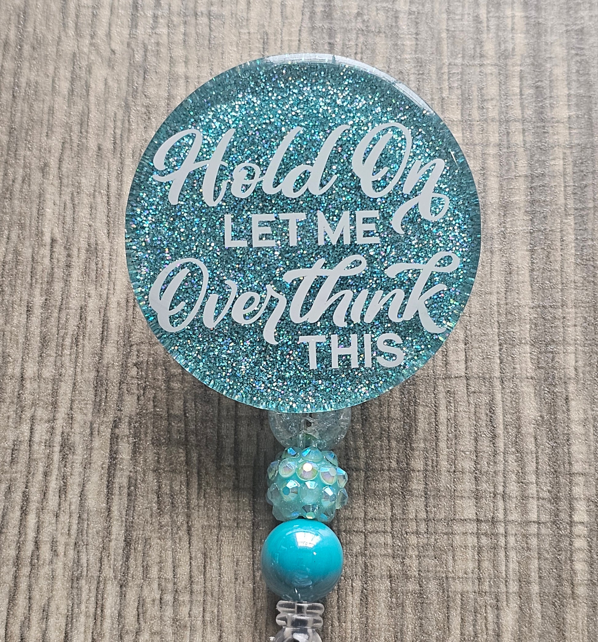 A badge reel stating Hold On Let Me Overthink available in a variety of colors.