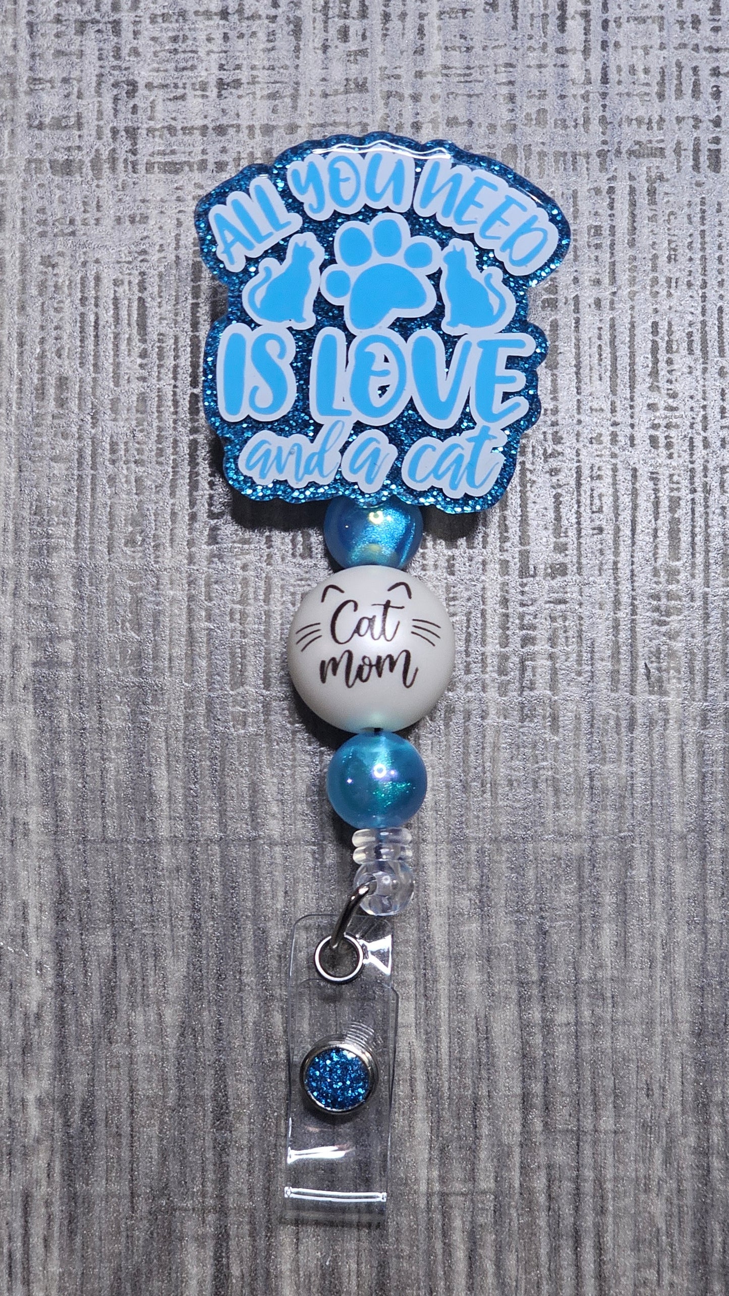 Badge holder with 'All you need is love and a cat' text on a gray textured background