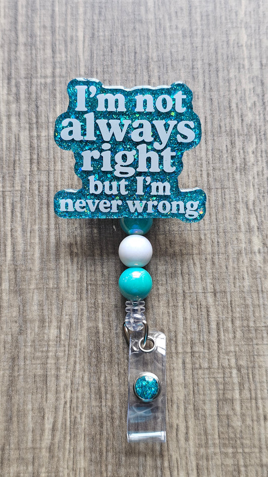 A retractable badge reel with a glittery teal blue sign that reads 'I'm not always right but I'm never wrong' in white text, decorated with white and teal beads, shown on a gray wood-textured background.