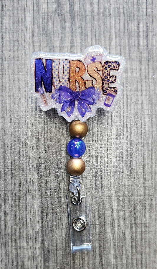 Badge reel with "Nurse" written in purple and gold lettering, accessorized with purple and gold beads.
