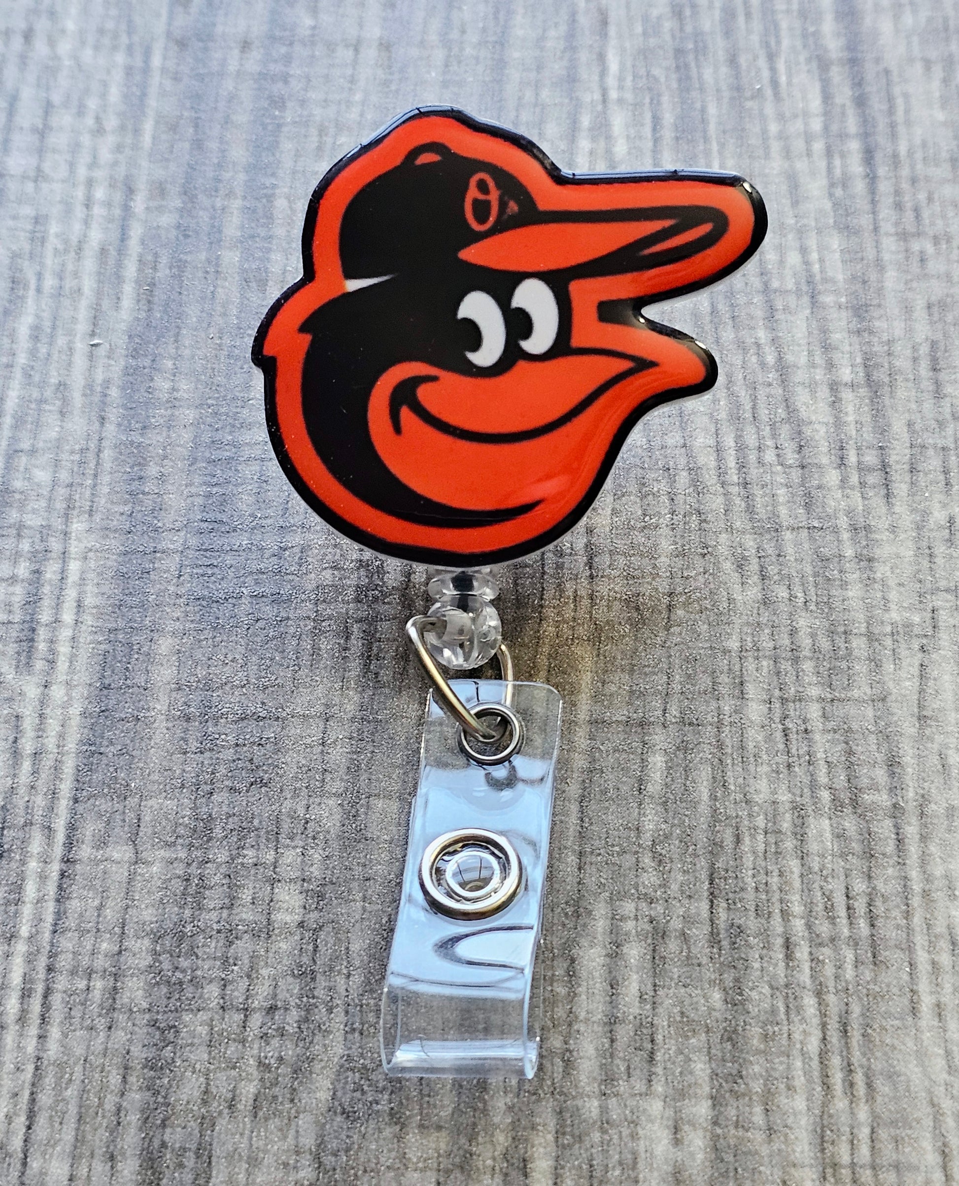 Handcrafted Orioles-inspired bird mascot badge reel with baseball beads  white acrylic finish.