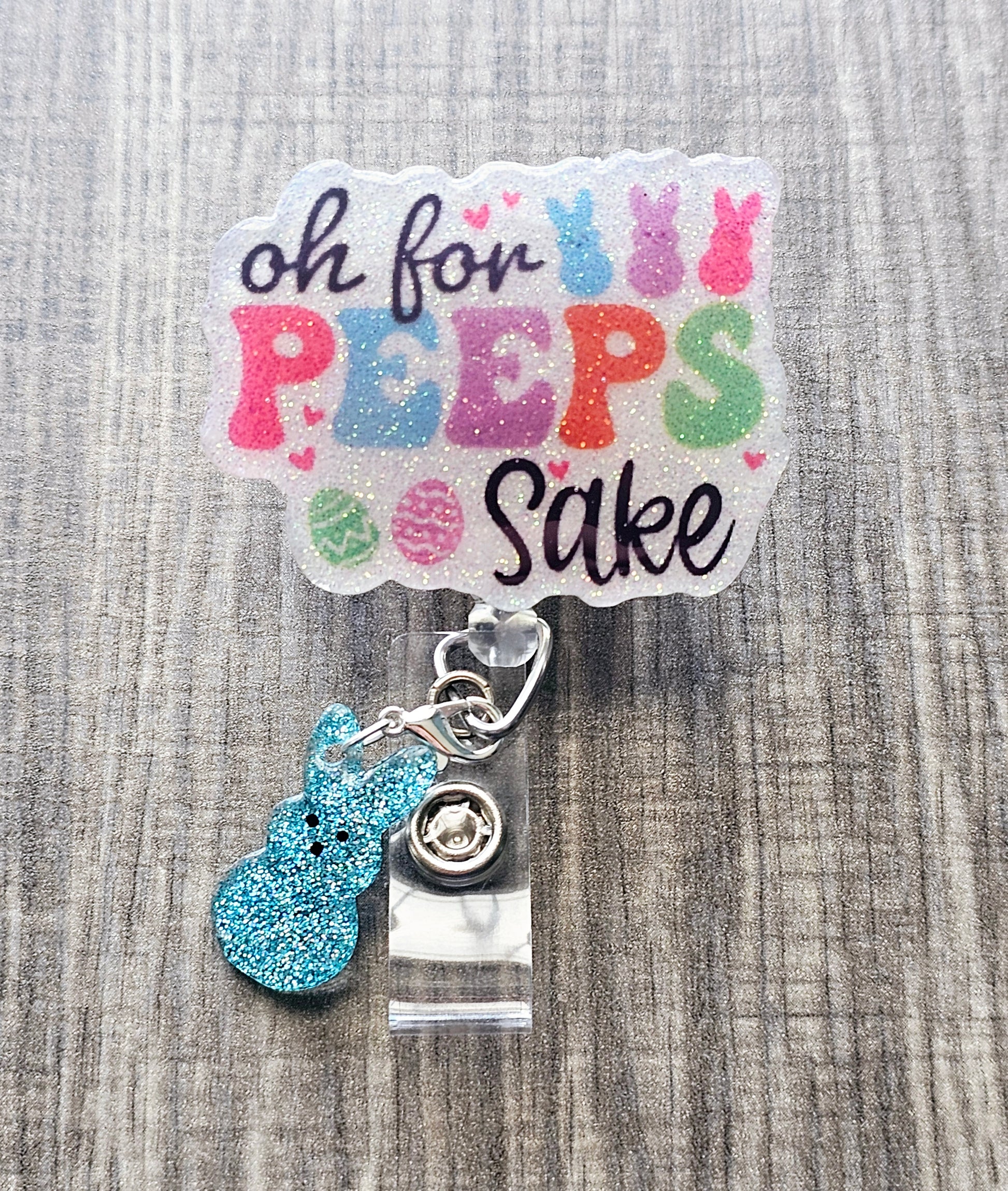 An Easter-themed badge reel with "Oh For Peeps Sake" text and a glittery bunny clip attachment.