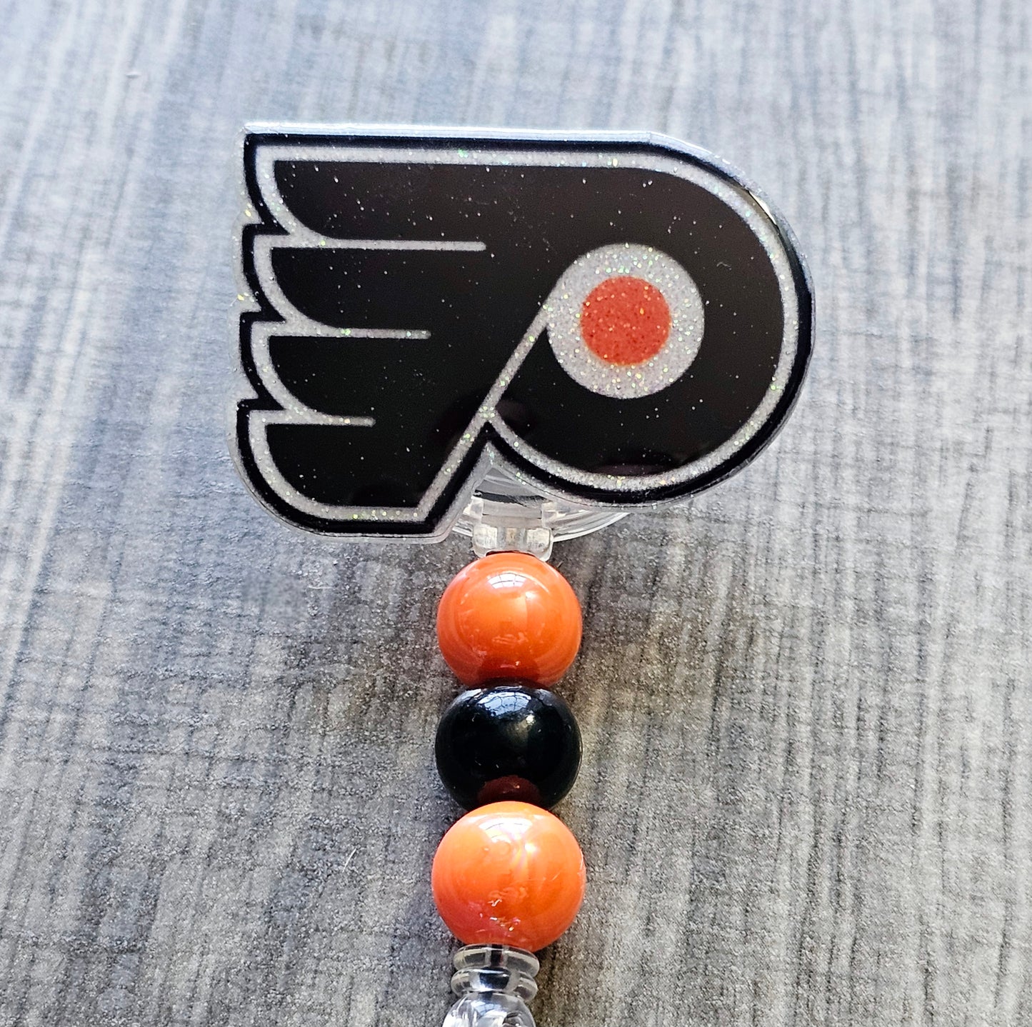 Philadelphia hockey badge reel shaped like classic logo, available in white acrylic or glitter.