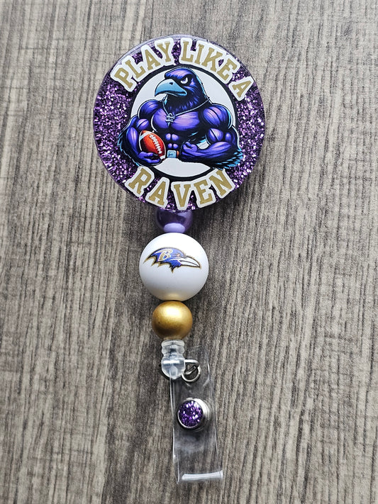 a badge reel displaying a powerful Raven holding a football along with the words Play Like A Raven around it 