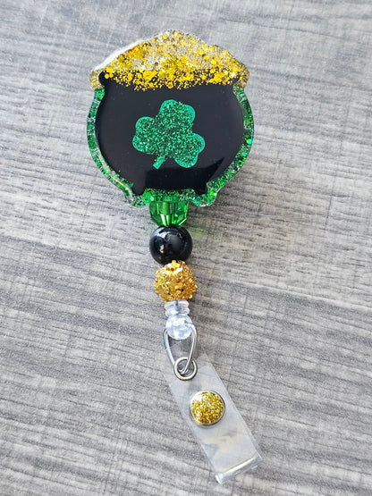 A badge reel featuring a pot filled with gold and adorned with a lucky clover symbol!