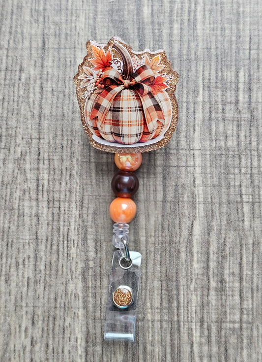 A retractable badge reel featuring a festive patchwork pumpkin design for the fall season.