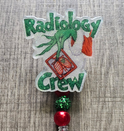 A badge holder/ badge reel featuring a mischievous grinch  design  in a Christmas sweater, holding a radiology image .