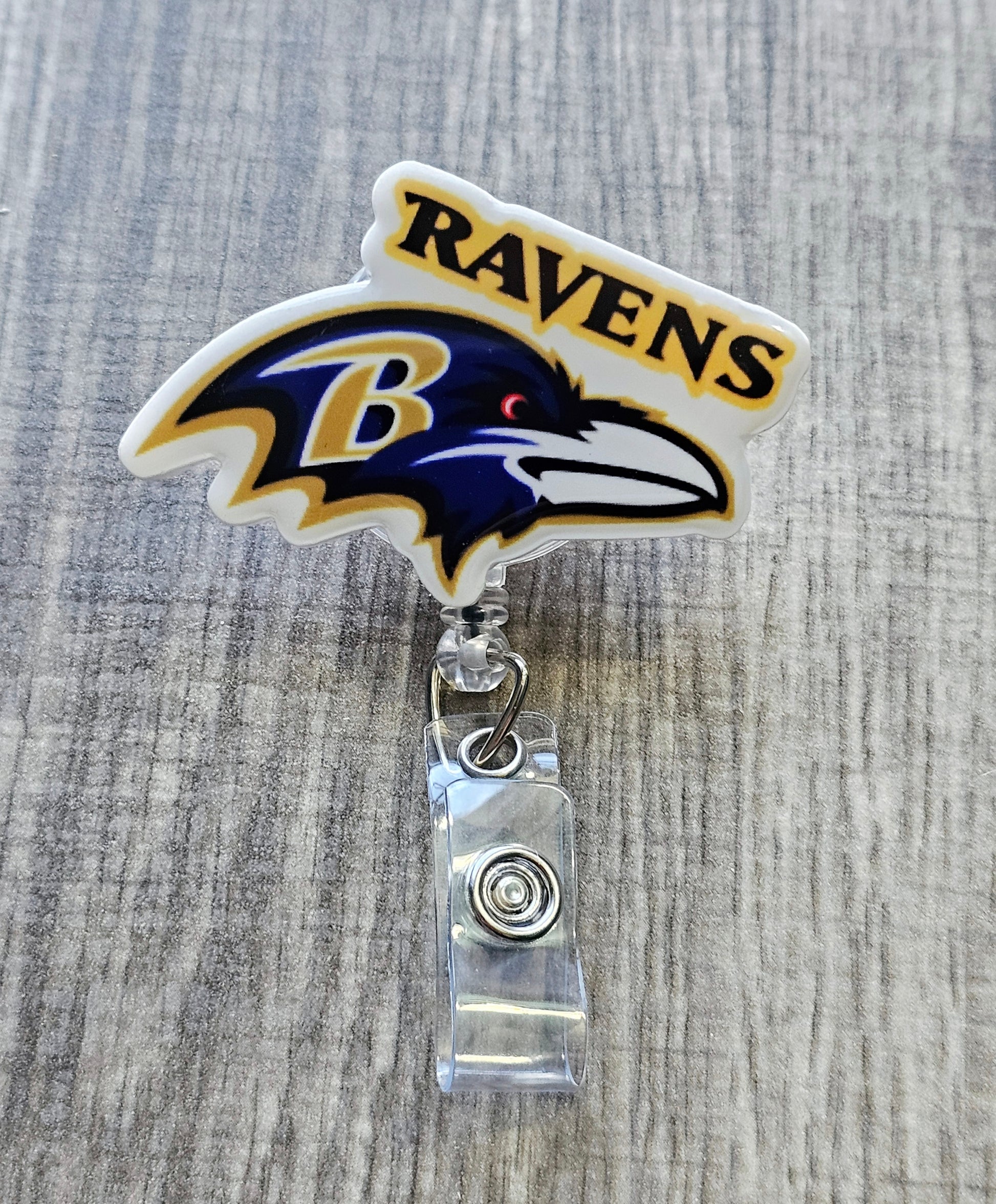 Ravens-inspired bird mascot badge reel with football beads, crafted in white acrylic.