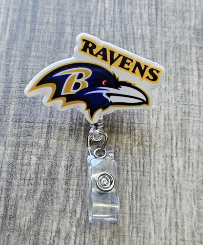 Ravens-inspired bird mascot badge reel with football beads, crafted in white acrylic.