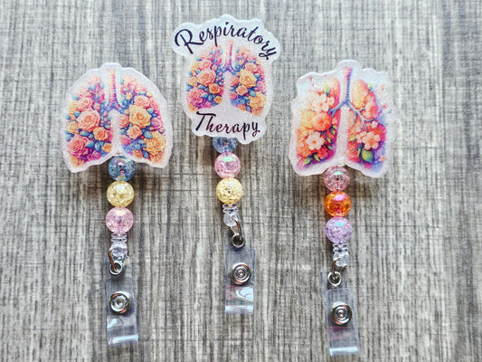 A collection of three respiratory therapy badge reels featuring floral lungs and respiratory system designs.