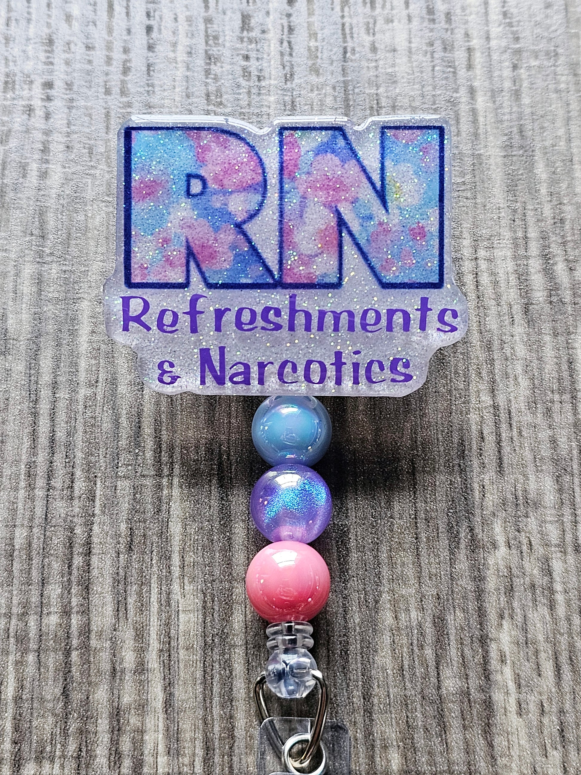 A badge reel featuring the letters "RN" with the phrase "Refreshments & Narcotics" in a fun, humorous design.