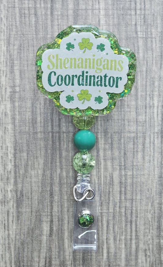 Green St. Patrick's Day badge reel with "Shenanigans Coordinator" text and festive shamrock accents.
