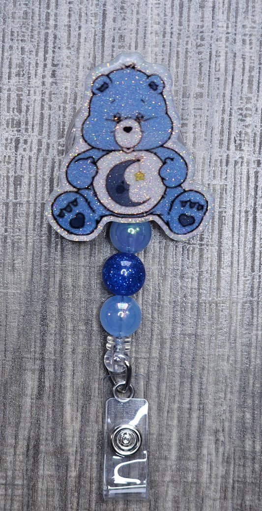 Blue bedtime  care bear-shaped badge holder on a textured gray background