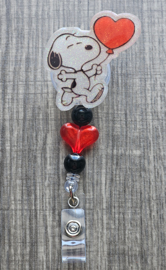 Snoopy holding a heart shaped balloon badge reel with red and black heart beads.