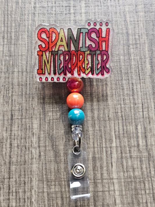 White acrylic badge reel with "Spanish Interpreter" written in colorful, creative lettering, accompanied by matching decorative beads.