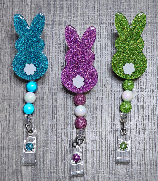 A set of three badge reels shaped like rabbits with glitter and beads in green, blue, and purple colors.