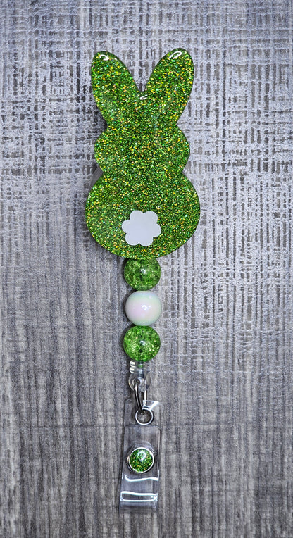 Green glittery bunny-shaped badge holder on a textured gray background