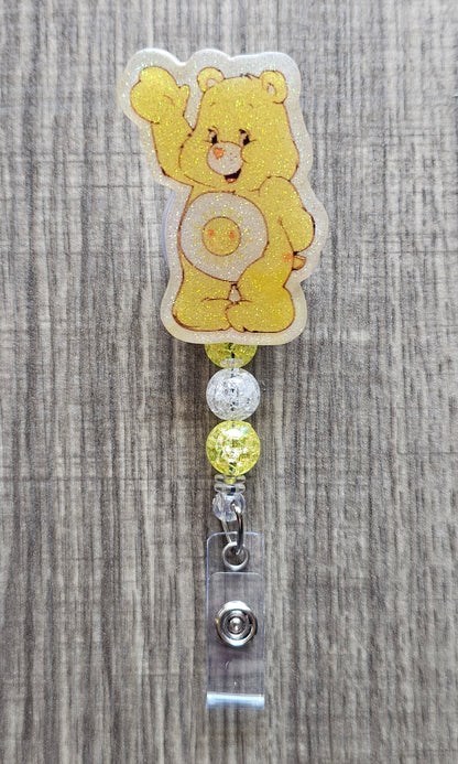 Smiling Sunshine Care Bear character badge reel with yellow and white beads on a badge holder.
