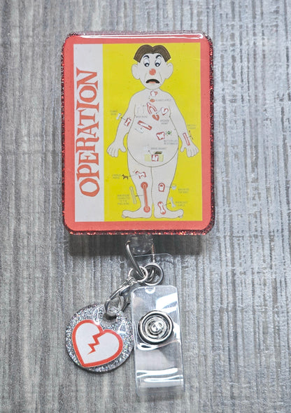 Retractable badge reel featuring the classic red-nosed patient from the Operation board game.