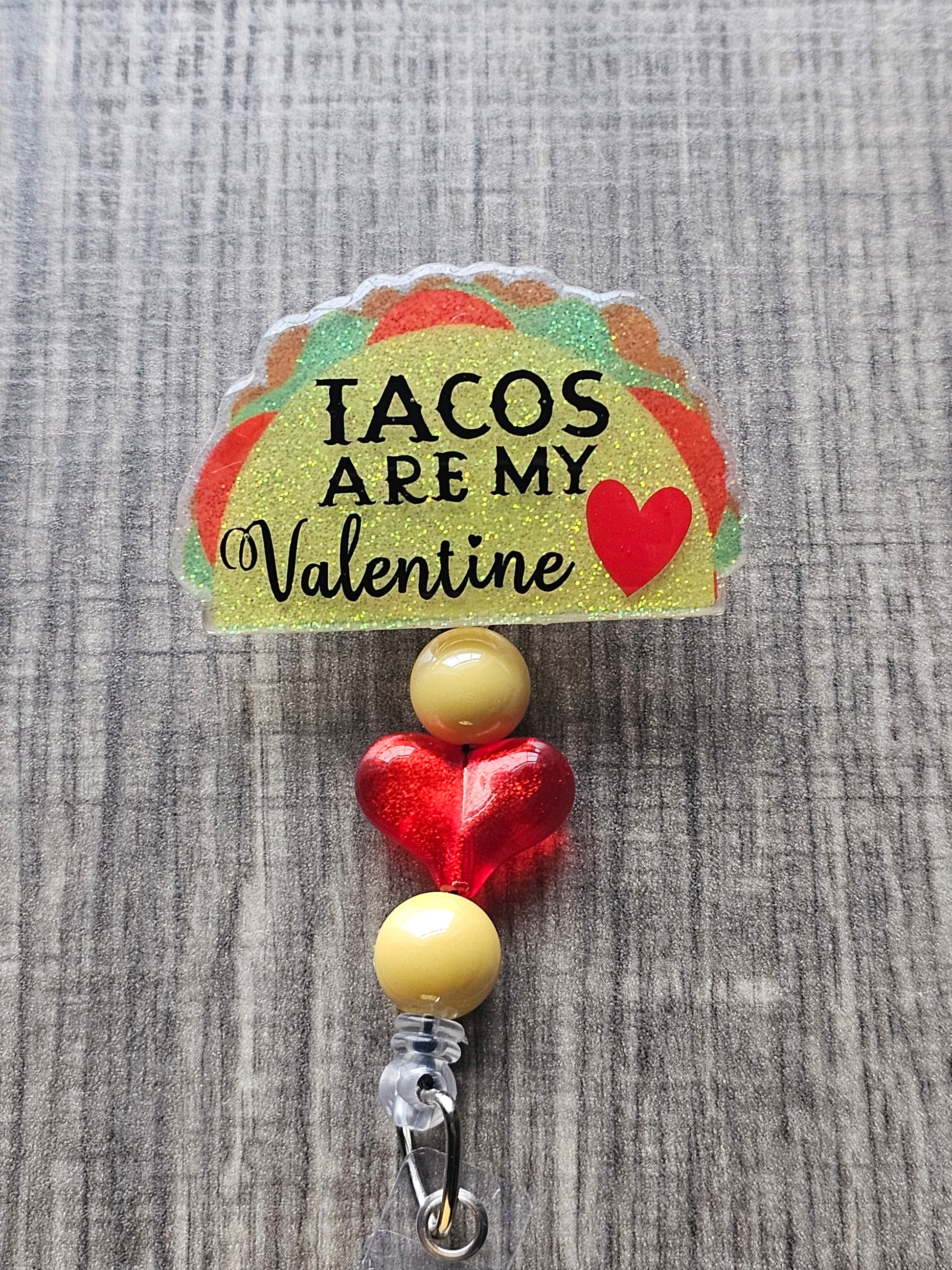 A taco shaped badge reel which states Tacos Are My Valentine with a heart beside it.