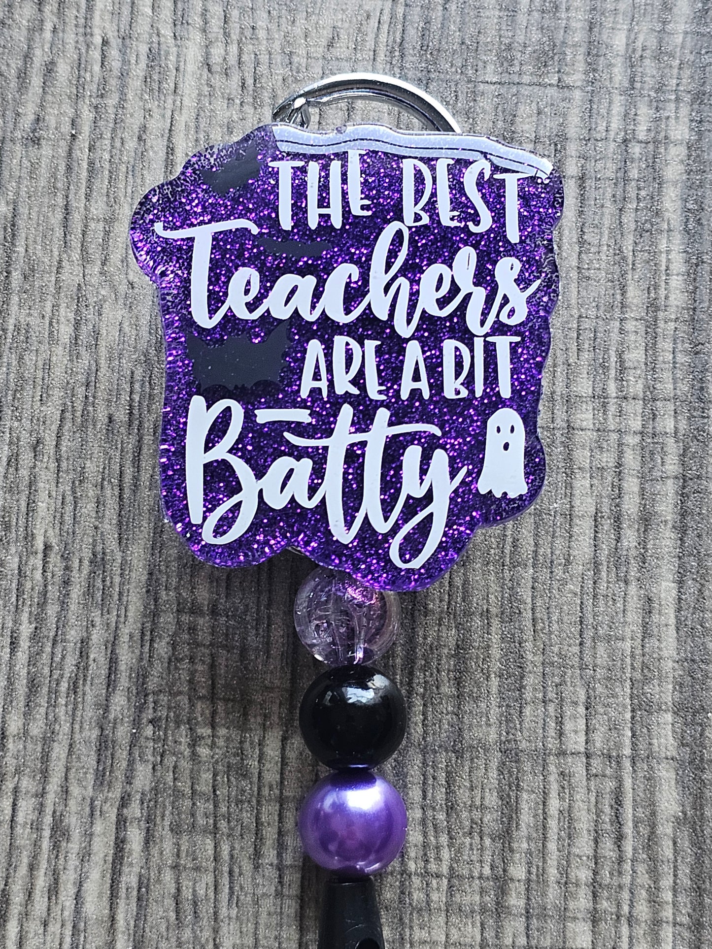 a badge reel stating the best teachers are a bit batty which incorporates bats and a ghost in the design 