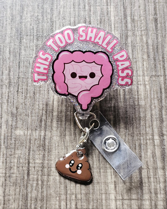 A badge reel featuring smiling intestines and a cute animated poop charm, along with the phrase "This Too Shall Pass.