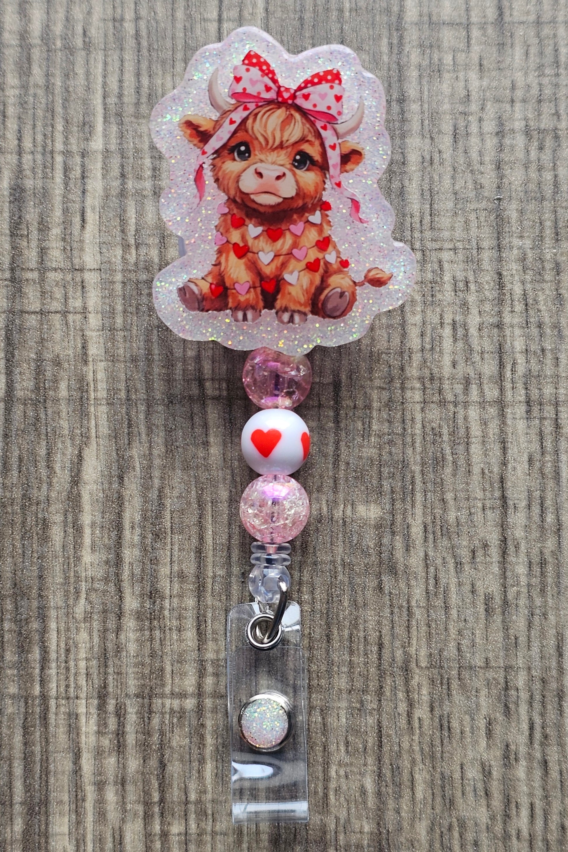 Cute highland cow badge reel with hearts and a bow on its head for Valentine’s Day