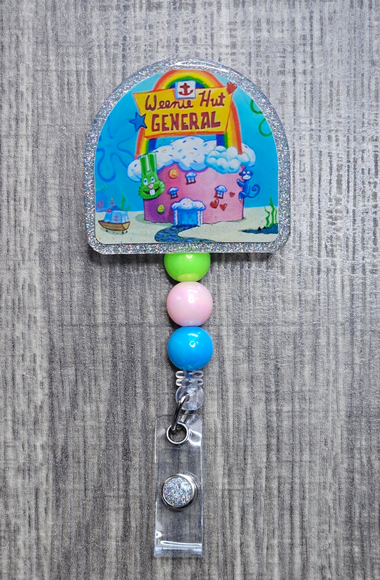 A colorful badge reel featuring the iconic hospital from SpongeBob  'Weenie Hut General'. It includes decorative beads and an alligator clip.